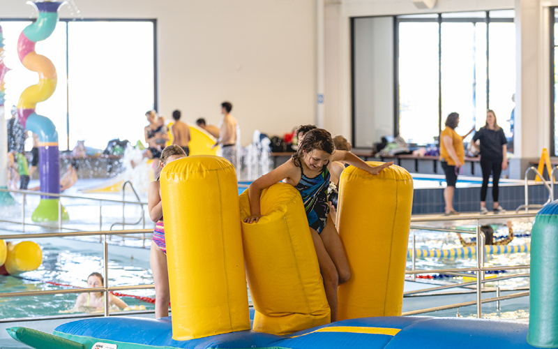 Photo of young girl running across a pool inflatable toy